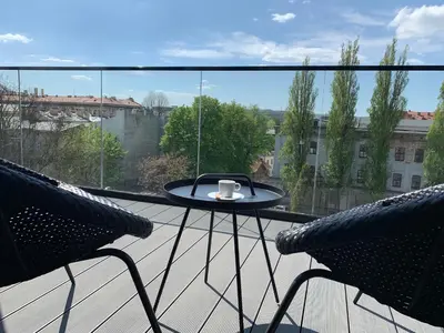 a balcony with two chairs and a table with a cup on it at AGIHOME Rajska 3 Apartments in Kraków