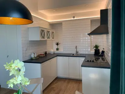a kitchen with white cabinets and black counter tops at AGIHOME Rajska 3 Apartments in Kraków