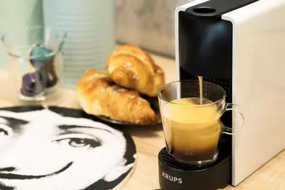 a coffee maker with a glass of coffee and donuts at Art Apartment in Kraków