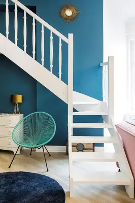 a white staircase in a room with a blue wall at Art Apartment in Kraków