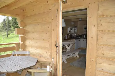 a door to a log cabin with a table and a kitchen at Mountain chalet SmoLenisko domek w górach in Nowy Targ