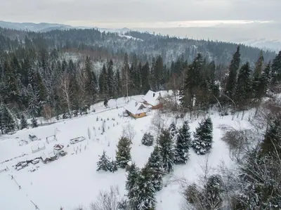a snow covered field with a house and trees at Mountain chalet SmoLenisko domek w górach in Nowy Targ