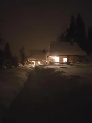 a house covered in snow at night with lights at Mountain chalet SmoLenisko domek w górach in Nowy Targ