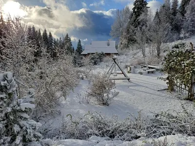 a snow covered yard with a house in the background at Mountain chalet SmoLenisko domek w górach in Nowy Targ
