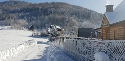 a house covered in snow next to a fence at Zawoja hrabkowa Jastrzębowka in Zawoja