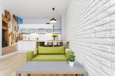 a living room with a green couch against a brick wall at Apartments Harmonica Trynitarska by Noclegi Renters in Kraków