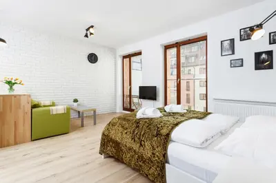 a white bedroom with a bed and a living room at Apartments Harmonica Trynitarska by Noclegi Renters in Kraków