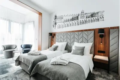 a bedroom with two beds and a chair at Focus Hotel Premium Kraków in Kraków