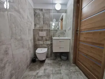 a bathroom with a toilet and a sink and a door at Apartamenty u Krystyny in Klikuszowa