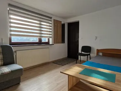 a bedroom with a bed and a chair and a window at Apartamenty u Krystyny in Klikuszowa