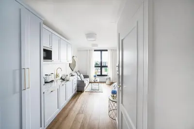 a white kitchen with white cabinets and a hallway at Apartament Golden Place 2 in Kraków