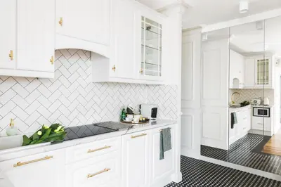 a white kitchen with white cabinets and black tiles at Apartament Golden Place 2 in Kraków