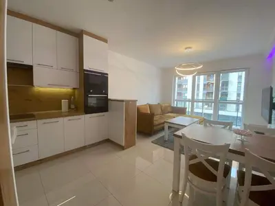 a kitchen and living room with white cabinets and a table at Apartament VIP in Kraków