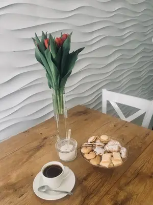 a vase of flowers and a plate of cookies and a cup of coffee at Apartament VIP in Kraków