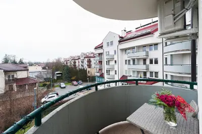 a balcony with a table with a vase of flowers on it at Bella Casa Premium Apartment - 117A Kobierzynska in Kraków