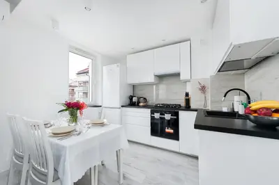 a kitchen with white cabinets and a white table and chairs at Bella Casa Premium Apartment - 117A Kobierzynska in Kraków