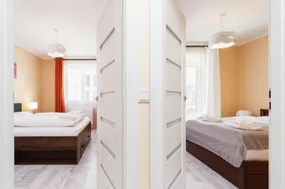 a bedroom with two beds and a sliding door at Apartments Kraków Zablocie by Noclegi Renters in Kraków