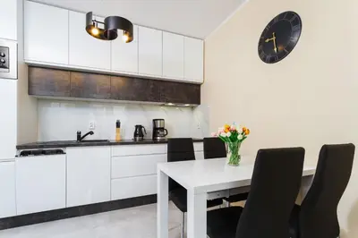 a kitchen with a table and a clock on the wall at Apartments Kraków Zablocie by Noclegi Renters in Kraków