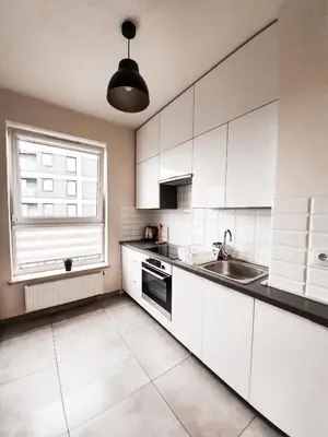 a kitchen with white cabinets and a sink and a window at Apartament Kraków Arena in Kraków