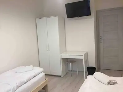 a room with two beds and a desk and a tv at Apartament Kraków Arena in Kraków