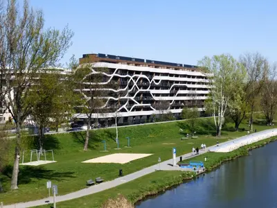 a building in a park next to a river at Apartament Nad Wisłą - Pianissimo in Kraków