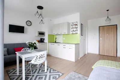 a kitchen and a living room with a table and chairs at Apartament Nad Wisłą - Pianissimo in Kraków