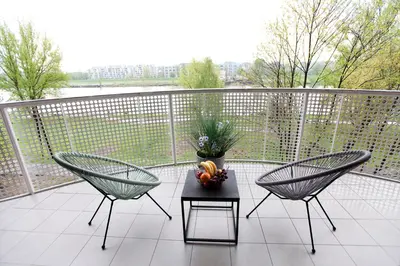 a balcony with two chairs and a table with a bowl of fruit at Apartament Nad Wisłą - Pianissimo in Kraków