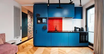 a kitchen with blue cabinets and a red window at Rajska Blue Luxury Apartment in Kraków