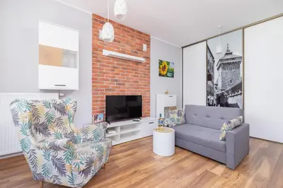 a living room with a chair and a tv at Apartments GO Rakowicka by Noclegi Renters in Kraków