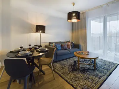 a living room with a table and a blue couch at Apartments GO Rakowicka by Noclegi Renters in Kraków