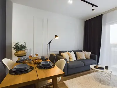 a living room with a table and a couch at Apartments GO Rakowicka by Noclegi Renters in Kraków