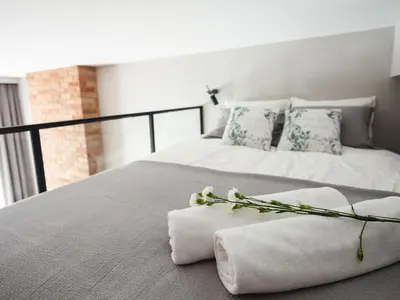 a bed with towels and flowers on top of it at Loft Apartment Cracow Old Town 3min Main Sq in Kraków