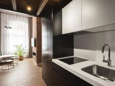 a kitchen with black and white cabinets and a sink at Loft Apartment Cracow Old Town 3min Main Sq in Kraków