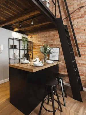 a kitchen with a counter and stools in front of a brick wall at Loft Apartment Cracow Old Town 3min Main Sq in Kraków