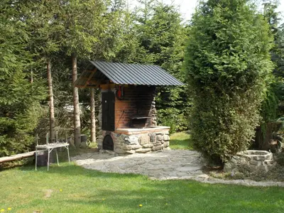 a stone fireplace in a garden with a roof at Noclegi pod Brzegiem in Zawoja