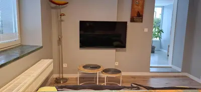 a living room with two stools and a tv on the wall at Noclegi pod Brzegiem in Zawoja