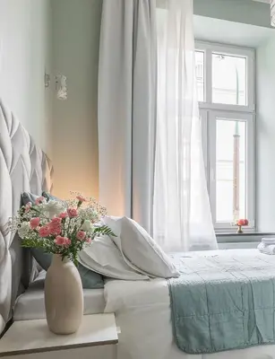 a white bedroom with a bed with a vase of flowers at Platinum Suites in Kraków