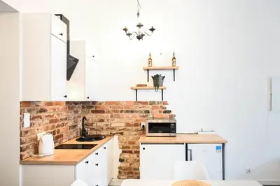 a kitchen with white cabinets and a brick wall at D&A Apartmetns Lenartowicza in Kraków