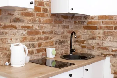 a kitchen counter with a sink and a brick wall at D&A Apartmetns Lenartowicza in Kraków