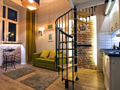 a living room with a green couch and a spiral staircase at Studio blisko Wawelu in Kraków