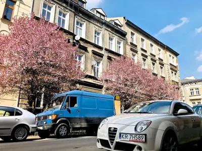 a blue truck and a silver car parked on a street at Studio blisko Wawelu in Kraków