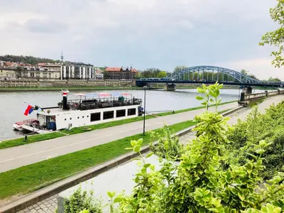 a boat on the river with a bridge in the background at Studio blisko Wawelu in Kraków