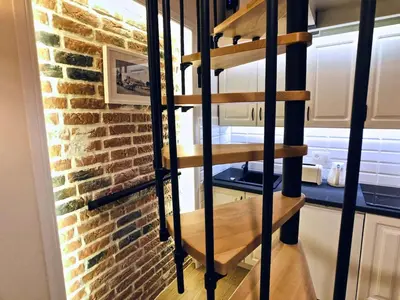 a wooden spiral staircase in front of a brick wall at Studio blisko Wawelu in Kraków
