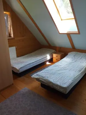 two beds in a attic room with a window at Zawojka in Zawoja