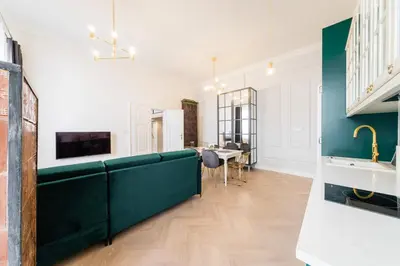 a living room with a green couch and a table at Apartament Deluxe Old Town św. Krzyża WAWELOFTS in Kraków