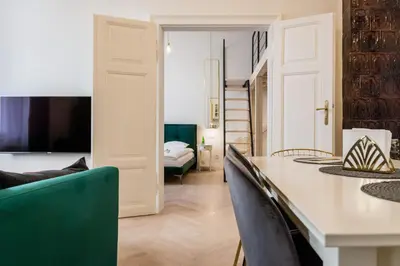 a living room with a table and chairs and a bedroom at Apartament Deluxe Old Town św. Krzyża WAWELOFTS in Kraków
