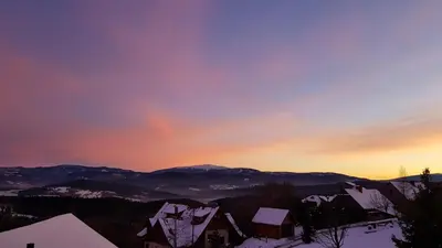 a winter sunset with snow covered buildings and mountains at Podbucznik 3 Leskowiec in Targoszów