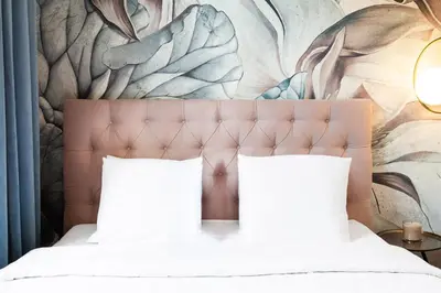 a bed with two pillows in front of a mural at HOUSEHOST Apartment: Łazarza street in Kraków