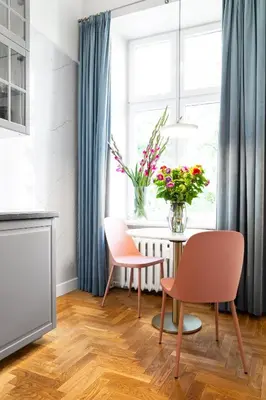 a dining room with two chairs and a table with flowers at HOUSEHOST Apartment: Łazarza street in Kraków