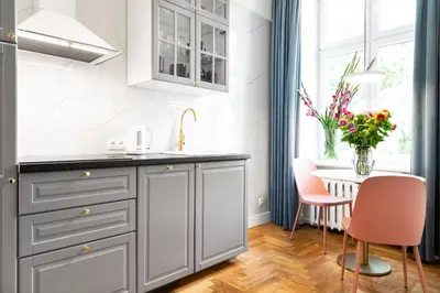 a kitchen with gray cabinets and a table with chairs at HOUSEHOST Apartment: Łazarza street in Kraków